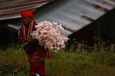 Midsection of person standing by flowers