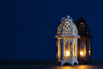 Illuminated lantern against blue sky at night