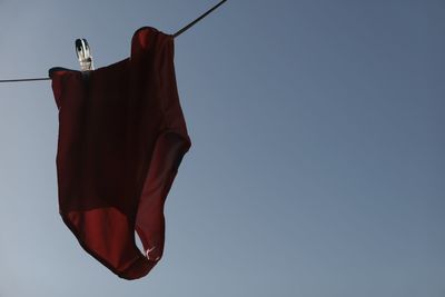 Low angle view of clothes drying against clear blue sky