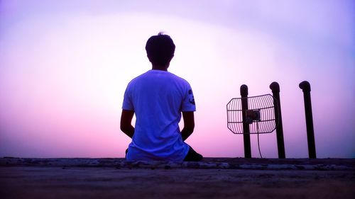 Rear view of friends standing on land against sky during sunset