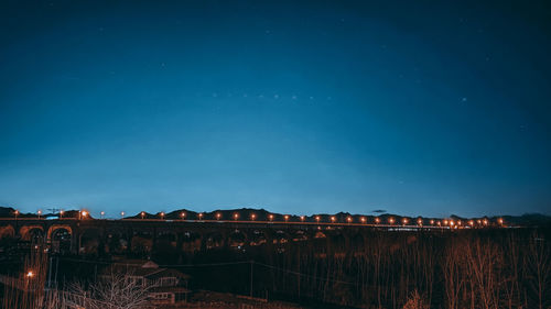 Illuminated buildings against clear sky at night