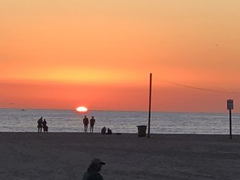 Silhouette people on beach against sky during sunset