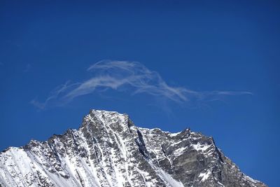 Low angle view of snowcapped mountain against blue sky