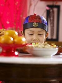 Close-up of boy picking food in container at table