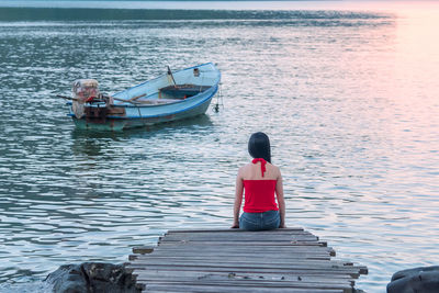 Rear view of woman sitting on lake