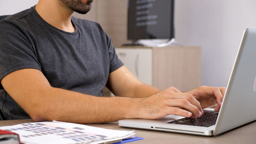 Midsection of man using laptop at office