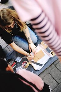 High angle view of woman holding hands sitting outdoors