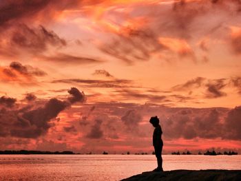 Silhouette of people standing on landscape against cloudy sky