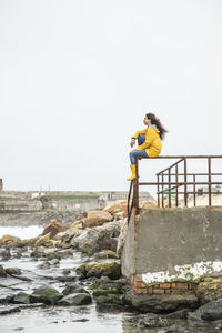 Young woman admiring view while sitting on railing