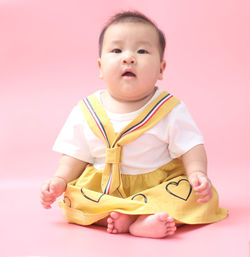 Portrait of cute baby against pink background