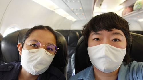 Two asian women travel with mask on during plane flight selfie