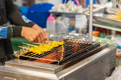 Cropped hand of person preparing meat on barbecue grill