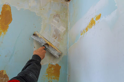 Cropped hand of man scraping paint at home