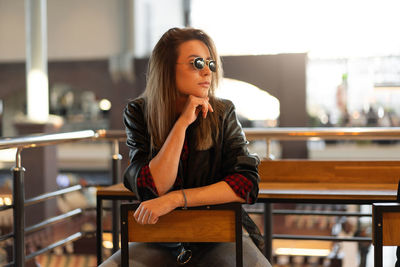 Young woman wearing sunglasses sitting on table at cafe