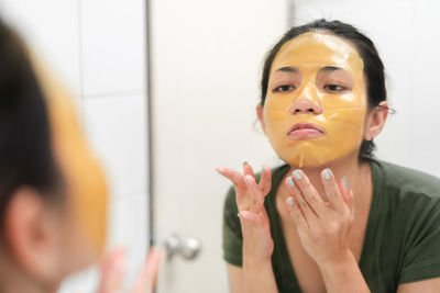 Close-up of woman applying facial mask