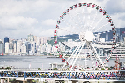 Ferris wheel in city against cloudy sky