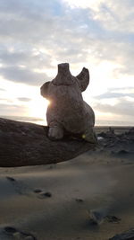 Close-up of statue on beach against sky during sunset
