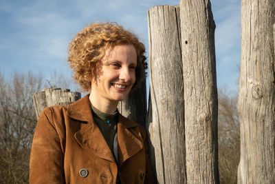 Smiling woman standing by fence