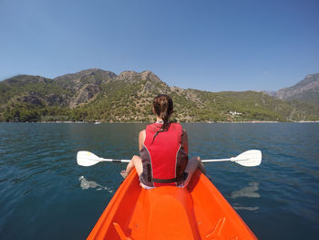 Rear view of woman sitting on kayak on lake