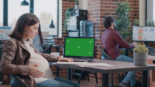 Pregnant woman working on laptop in office