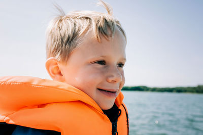 Portrait of happy young boy sat in a boat in summer in sweden