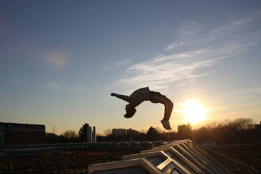 Low section of man skateboarding on skateboard against sky during sunset