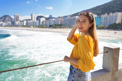 Portrait of stylish cheerful girl with waving ocean water of copacabana beach, rio de janeiro brazil