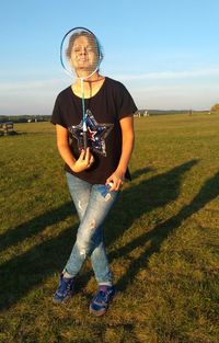 Full length of teenage girl holding umbrella on field