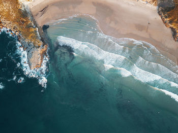 High angle view of sea shore with surfers and waves