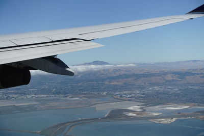 Airplane wing over mountains against clear blue sky