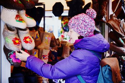 Woman looking at woolen shoes in shop during winter