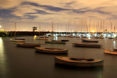 Sailboats moored on sea against sky at sunset