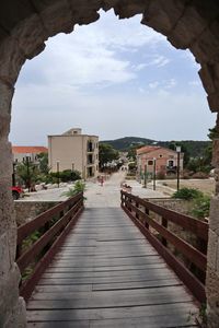 Empty footpath amidst buildings against sky