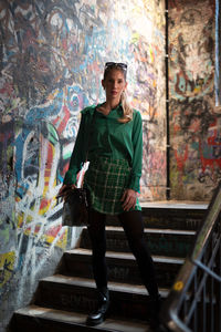 Full length of young woman standing against building