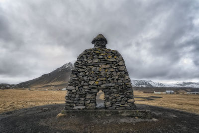 Stone structure at beach against cloudy sky during winter