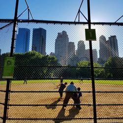 People playing baseball seen through chainlink fence