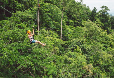 Full length of woman ziplining in forest