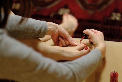 Low section of woman applying nail polish