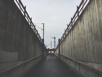 Pathway amidst walls against sky