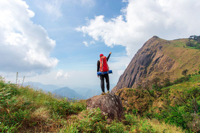 Rear view of man standing on mountain against sky