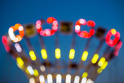 Defocused image of illuminated amusement park ride at night