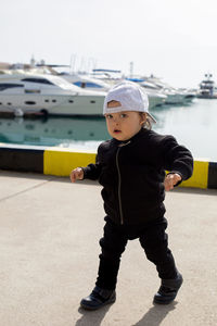 Little boy in a cap standing on the street in the seaport