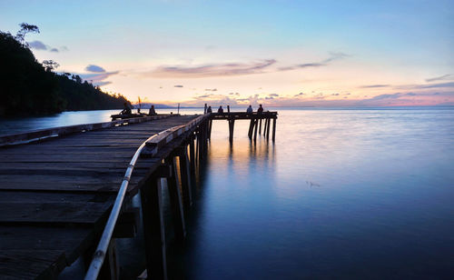 Pier over sea against sky during sunset