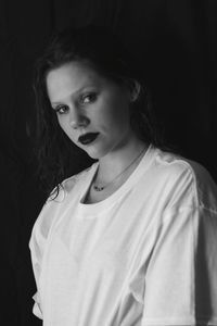 Portrait of teenage girl standing against black background