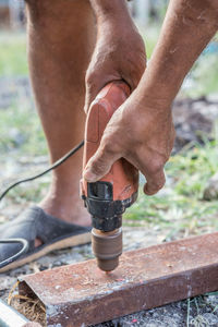 Low section of man drilling rusty metal