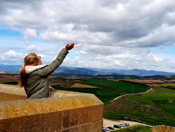 Girl standing at observation point against cloudy sky