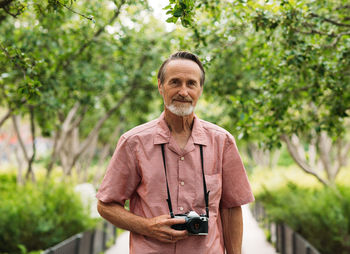 Portrait of young man standing against trees