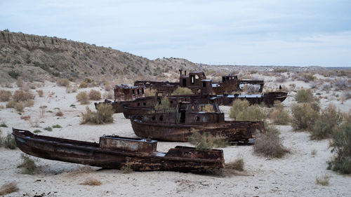 Abandoned boat on landscape against sky