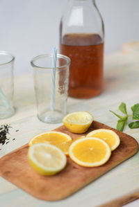 Slice lemons on wooden board by drinking glass with straws and jar of honey