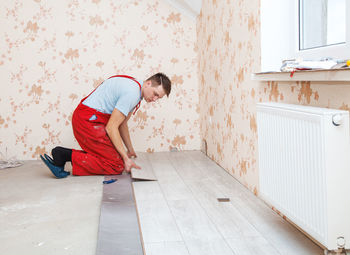 Man putting hardwood floor panels in home